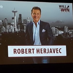 Photo of an overhead picture of Robert Herjavec with the Space Needle and Seattle skyline as a background.